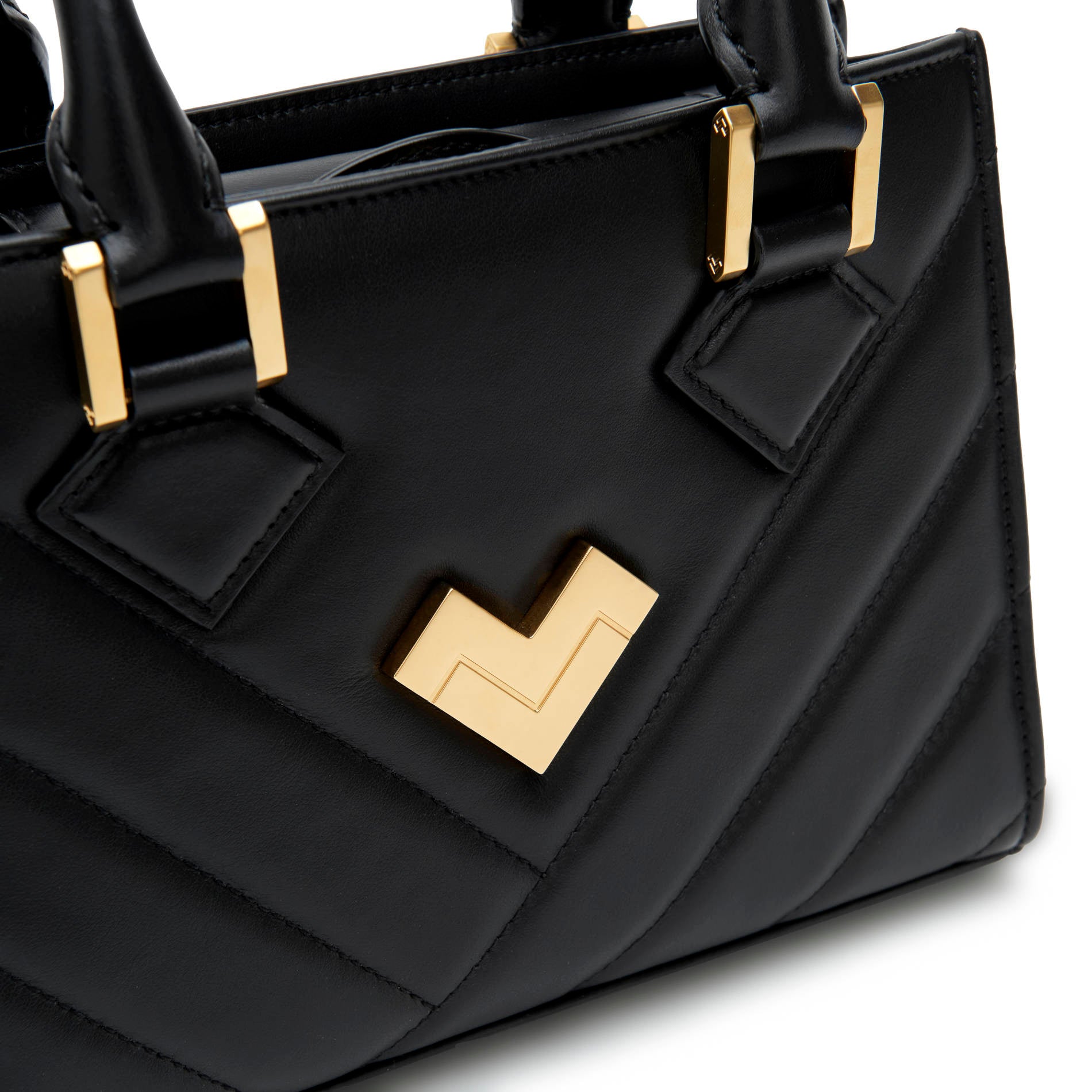 Black quilted leather crossbody bag close-up with gold-tone logo and hardware detail. Made in Italy