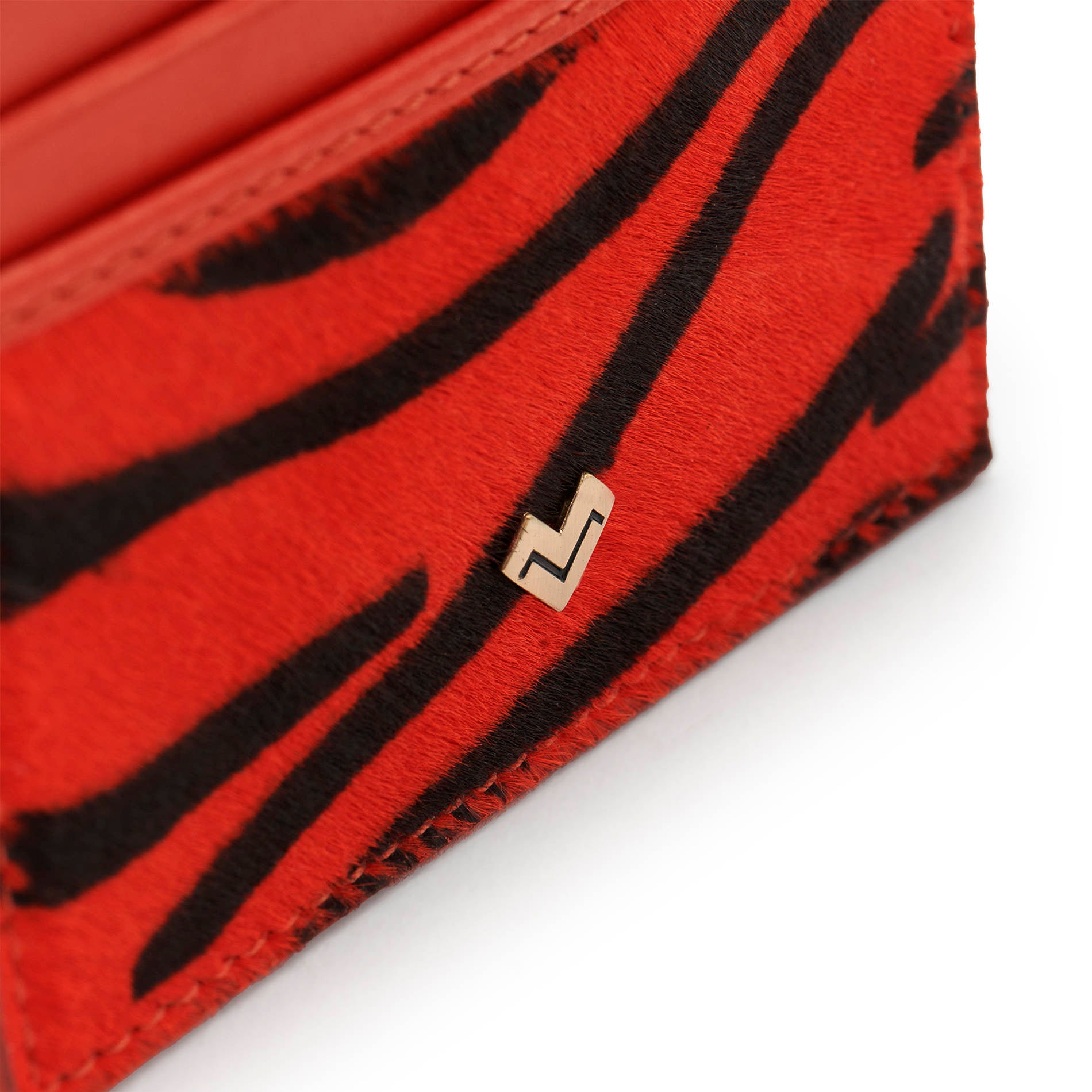 Detail of Mario Valentino zebra-print calfhair with iconic MV metal logo and refined texture finish