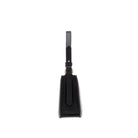 Side view of a structured black leather handbag with curved top edge, leather handle and detachable shoulder strap.