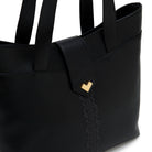 Black leather tote bag detail with gold logo and tonal embroidery.