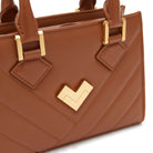 Brown leather bag close-up with gold hardware and matelassé detail, premium handbag. Made in Italy