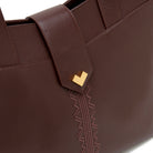 Gold logo and embroidery detail on moka leather tote bag, luxury handbag finish