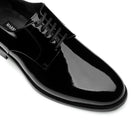 Close-up of men’s black derby shoes, patent leather and lace detail