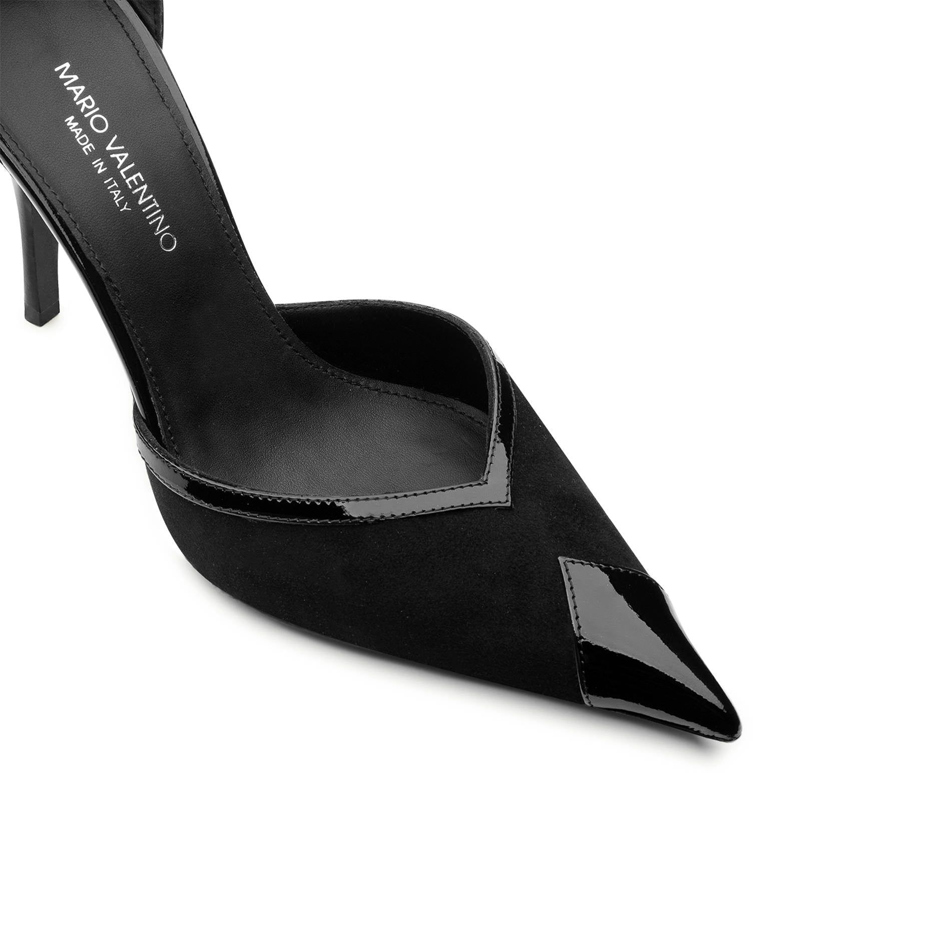 Detail of pointed toe black pumps in glossy patent leather and soft suede