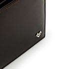Detail of Mario Valentino dark brown Italian embossed calfskin leather wallet with metal MV logo and smooth finish.