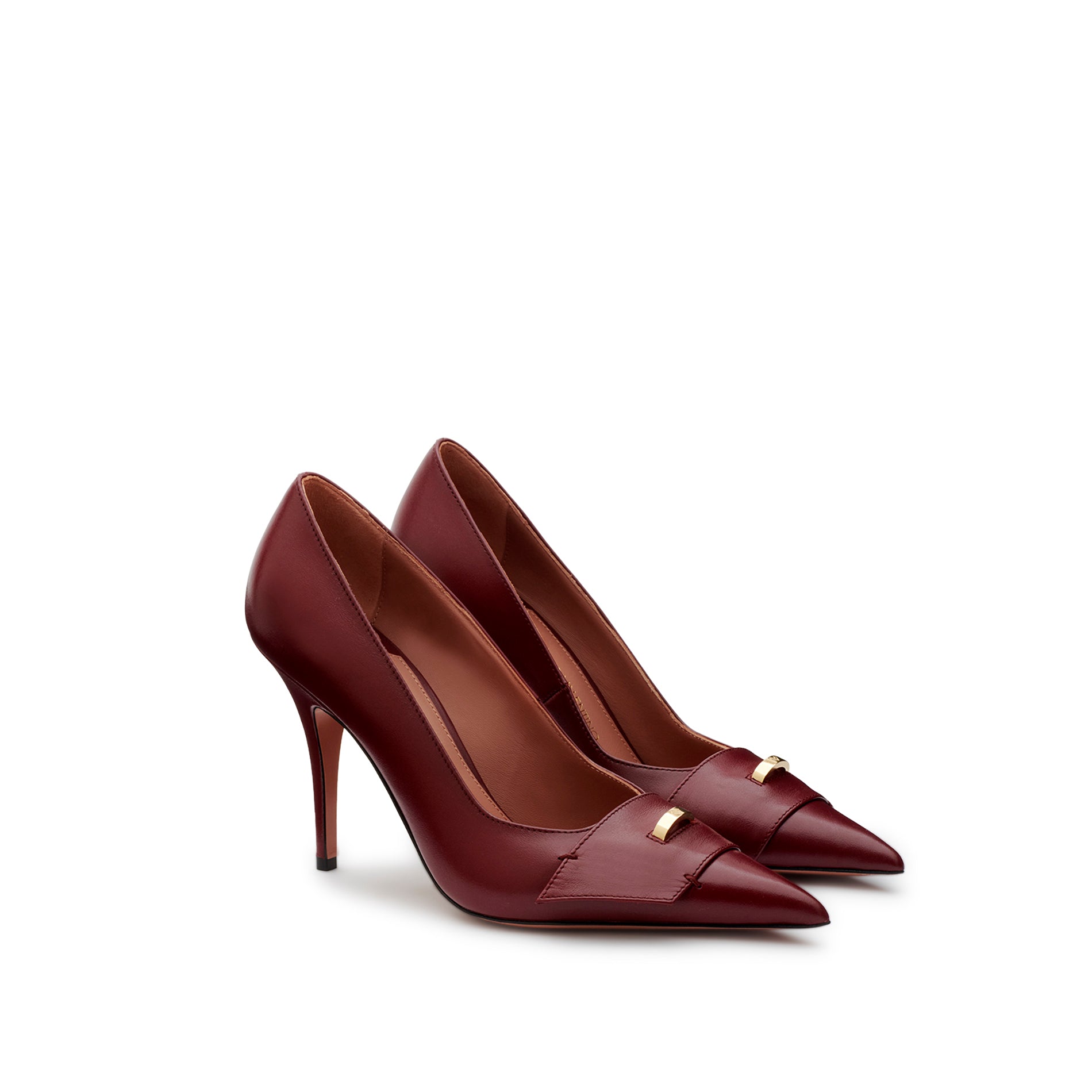 Pair of burgundy leather pumps with pointed toe, gold logo ring accessory and high stiletto heel. Made in Italy