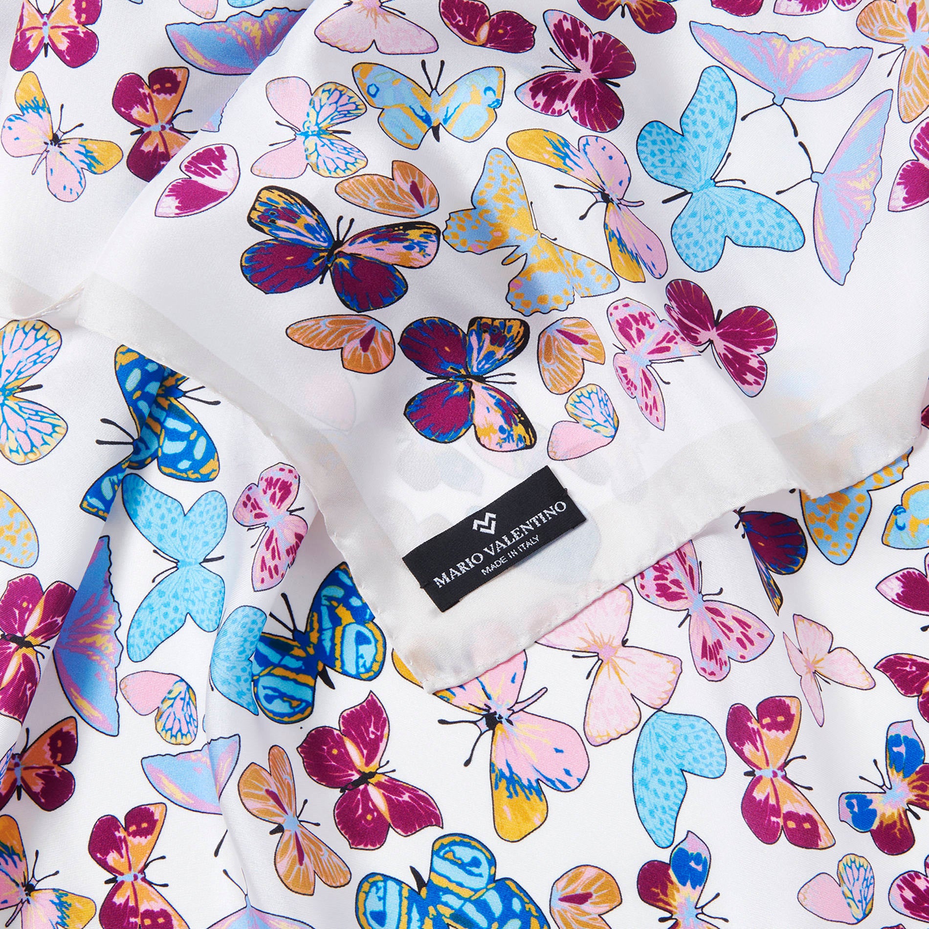 Close-up of Mario Valentino silk scarf fabric showing butterfly motif detail and refined Italian craftsmanship.