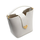 Close-up of the polished gold-finish MV-logo and magnetic snap closure on the white calf leather flap.