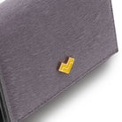 Detail of Mario Valentino grey calf hair leather wallet featuring a gold tone MV logo and a soft hair-on textured finish.