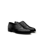 Pair of black calfskin brogue Oxford shoes by Mario Valentino, angled side view highlighting wingtip design